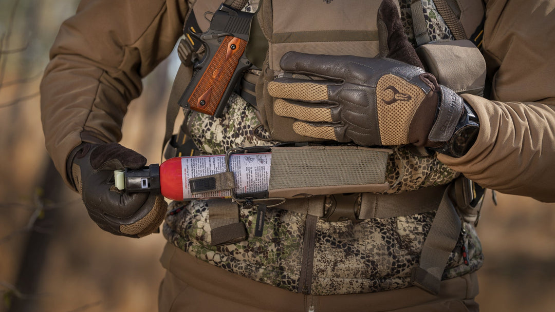 man pulling bear spray out of bino harness