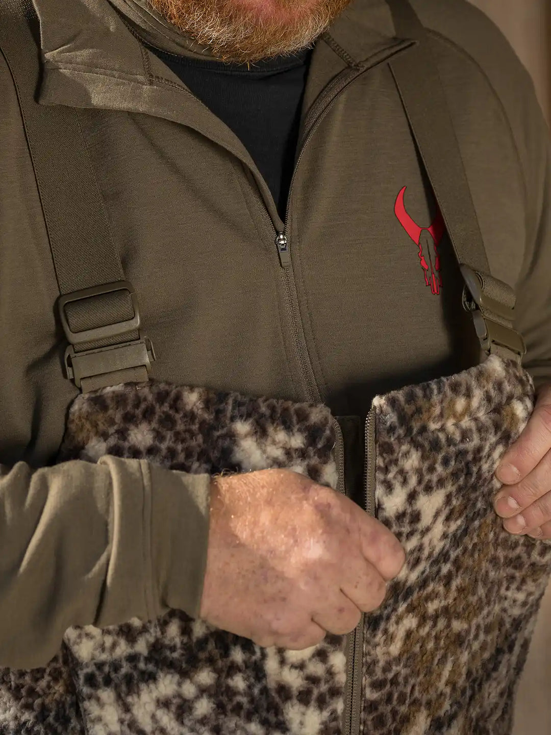 man zipping up hunting bibs