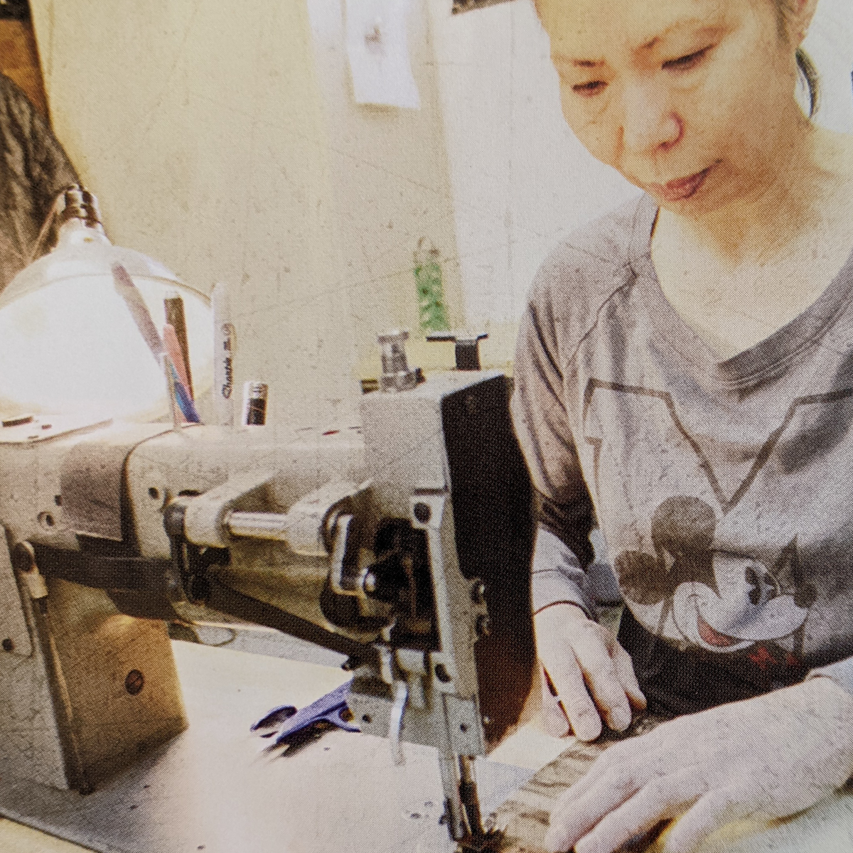 Person sewing Badlands gear at a machine; shirt features the Badlands skull logo and Mickey Mouse.
