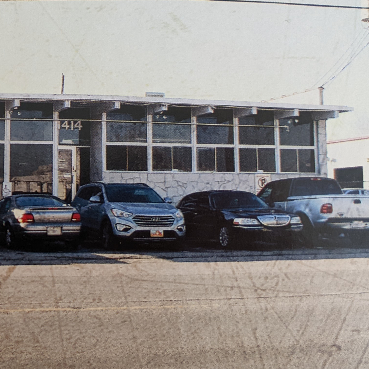 Four cars parked in front of the Badlands building at 414; accessible parking and entrance visible on the left.