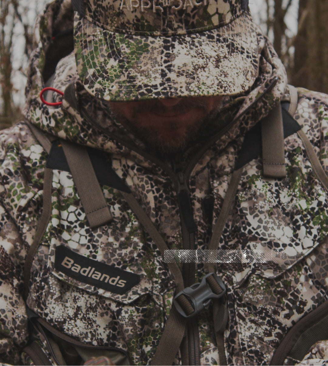 Man in Badlands camo jacket and hat outdoors; Badlands logo patch with skull visible on chest.