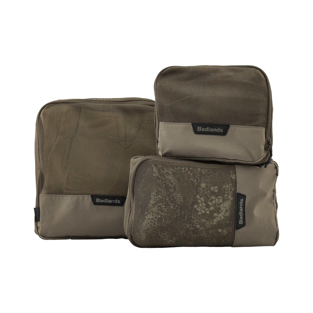 Three tan Badlands packing cubes with mesh fronts and logo tags, designed for organized gear storage.