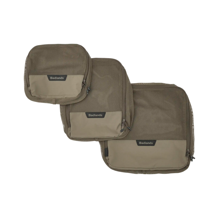 Three tan Badlands packing cubes with logo skull, mesh fronts, and zippers, shown in small, medium, and large sizes.