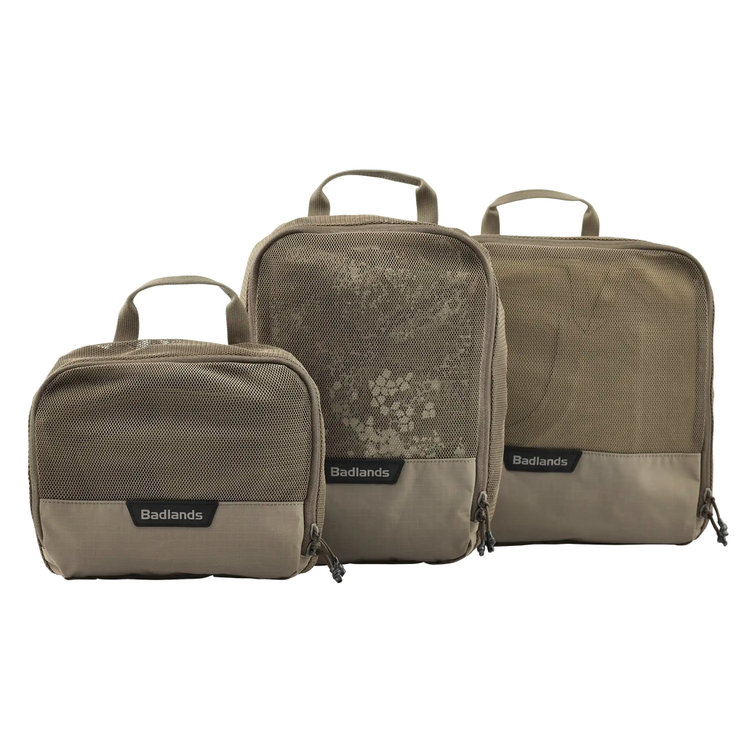 Three tan Badlands packing cubes with mesh fronts and handles, labeled with the Badlands logo for easy gear organization.