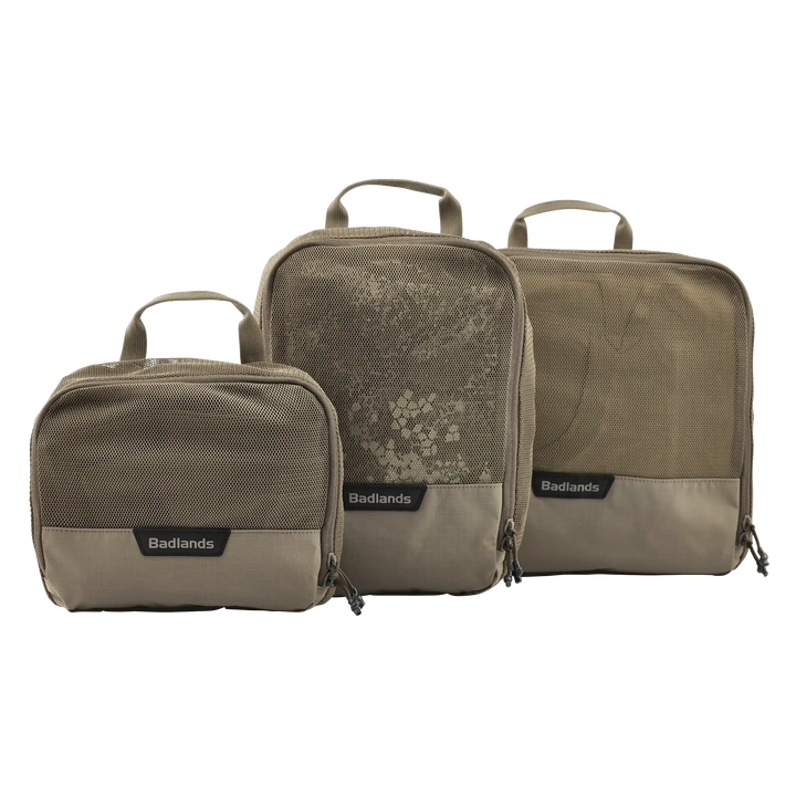 Three tan Badlands packing cubes with mesh fronts and handles, labeled with the Badlands logo for easy gear organization.