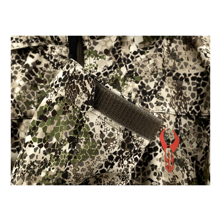 Close-up of Badlands camo jacket sleeve with Velcro strap and red Badlands skull logo.