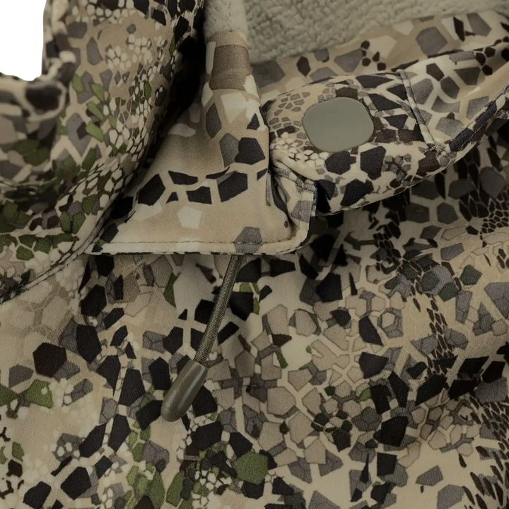 Close-up of Badlands camo fabric with drawstring and snap button; subtle Badlands skull logo pattern visible.