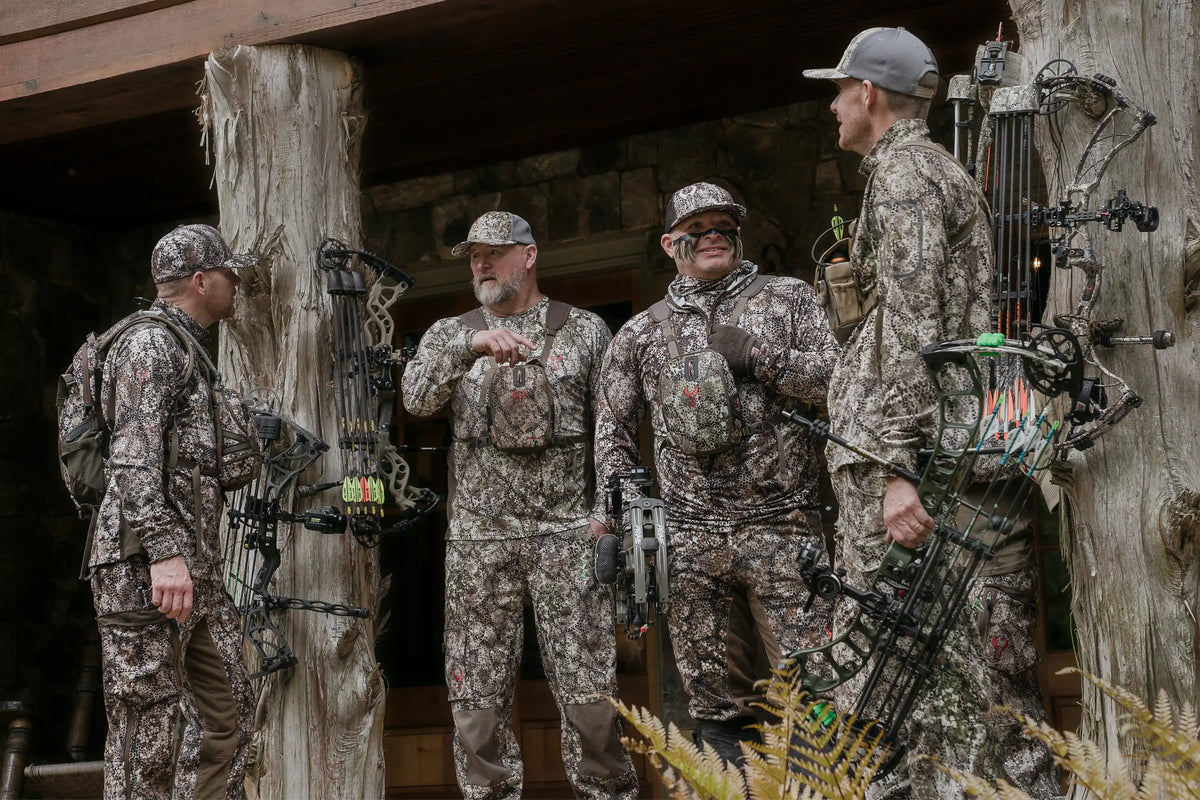 Four hunters in Badlands camo gear with bows, standing outdoors. Badlands skull logo visible on chest packs.
