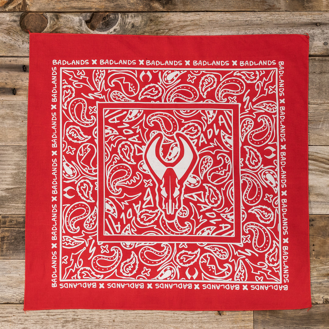 Red Badlands bandana with white paisley pattern and Badlands skull logo in the center; "Badlands" borders the edges.