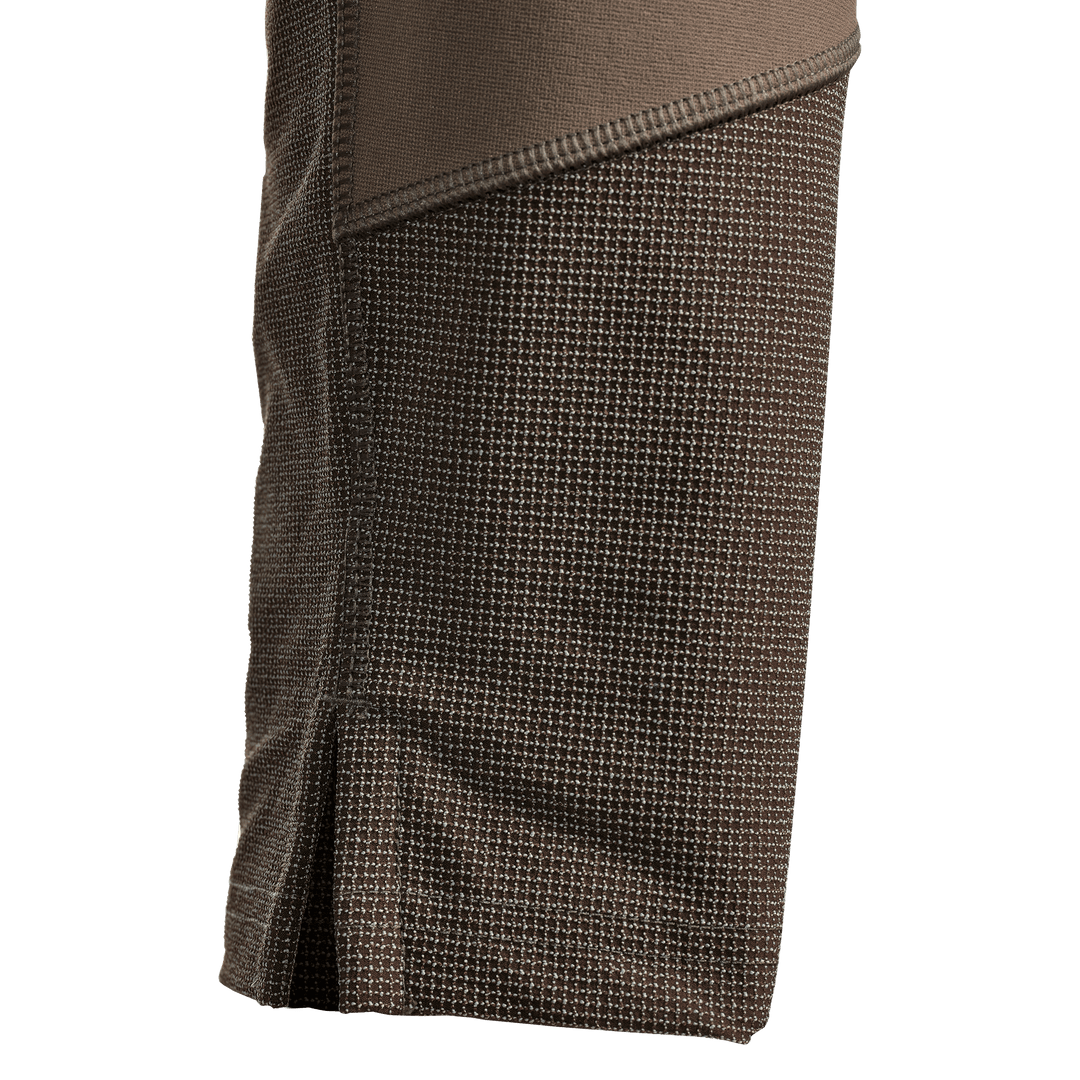 Close-up of brown Badlands hunting apparel fabric, showing textured grid pattern and reinforced stitching.