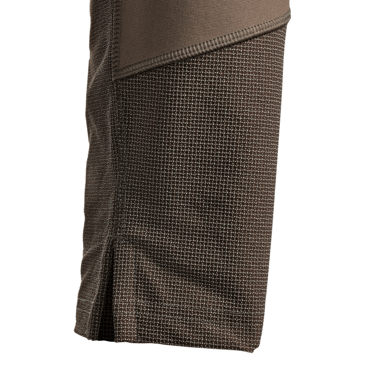 Close-up of brown Badlands hunting apparel fabric, showing textured grid pattern and reinforced stitching.