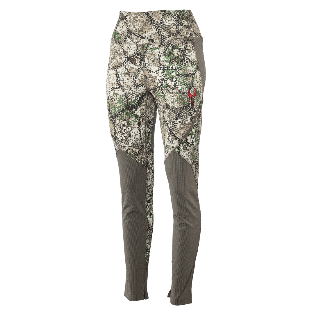 Women's camo hunting pants with Badlands skull logo on thigh; fitted, earth-tone pattern, lightweight, and durable.