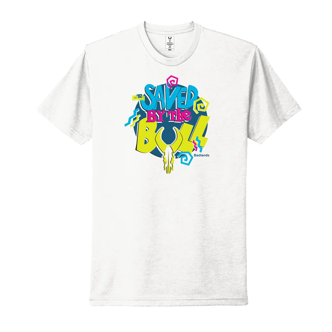 White t-shirt with "Saved by the Bull" text, colorful graphics, and a Badlands skull logo below the lettering.