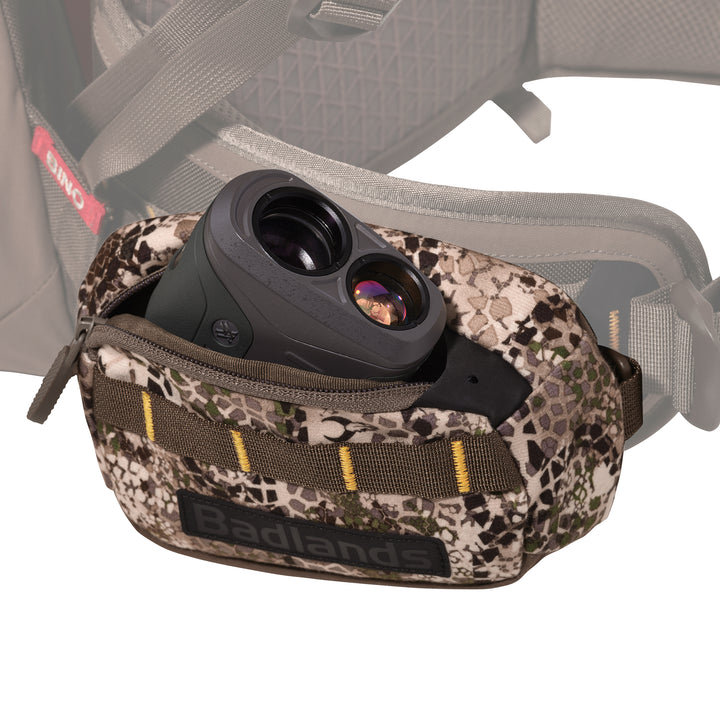 Badlands camo pouch with logo, holding a rangefinder, attached to a hunting pack waist belt.