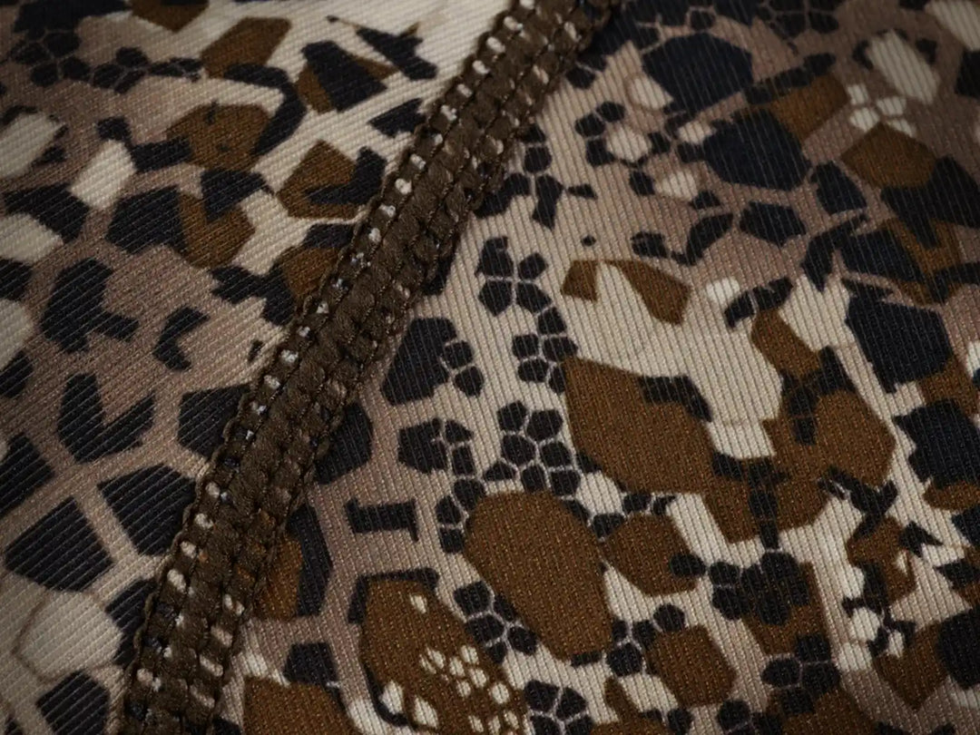 Close-up of Badlands camo fabric with visible stitching and subtle skull logo pattern in earth tones.