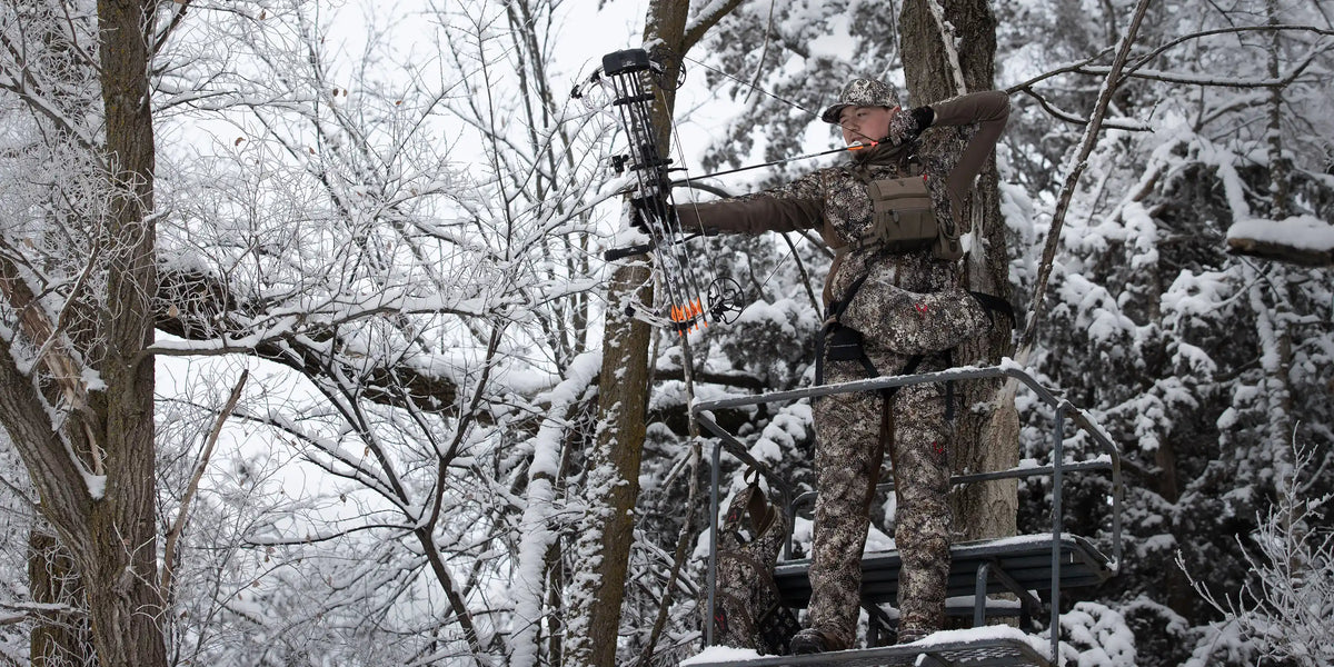 Hunter in Badlands camo draws a bow on a snowy treestand; Badlands skull logo visible on the gear.