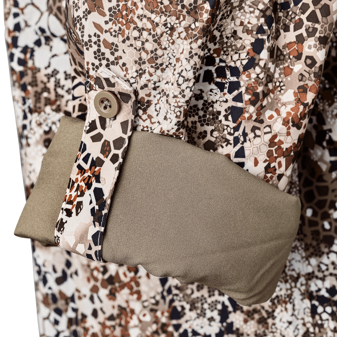 Close-up of a Badlands camo shirt sleeve with button cuff and olive green inner lining, featuring the Badlands skull logo.