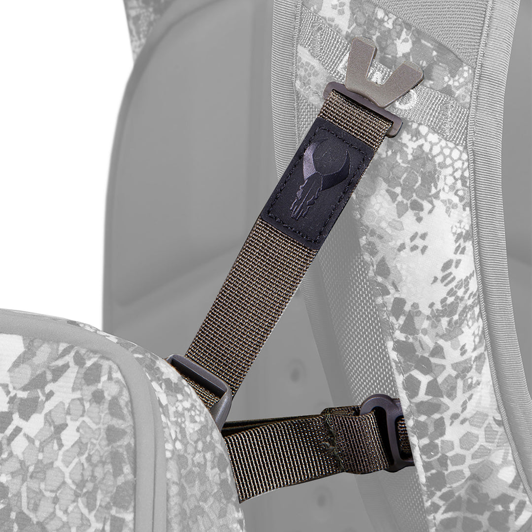 Close-up of a Badlands backpack strap with logo skull patch, showing adjustable buckle and camo fabric.