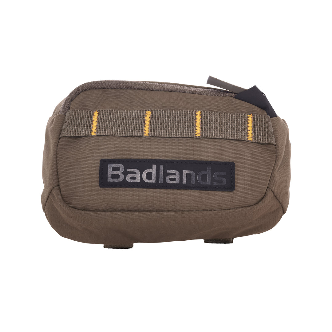 Tan Badlands pouch with yellow-stitched webbing and a black Badlands logo patch on the front, zipper closure on top.