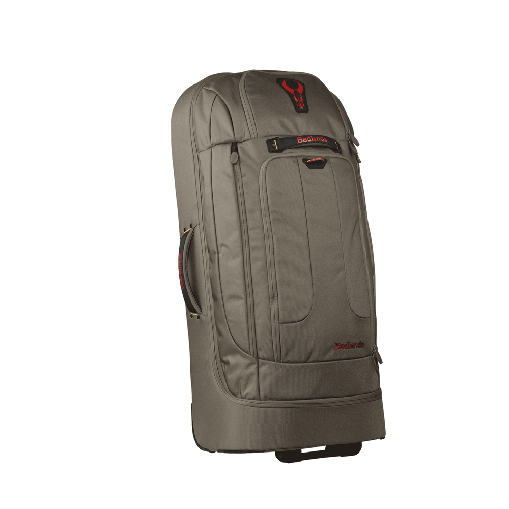 Large tan Badlands rolling duffel bag with side handle and red Badlands skull logo on top front panel.