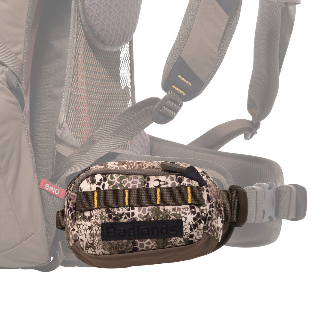 Camouflage Badlands waist pack with logo, attached to a backpack hip belt; designed for outdoor gear storage.