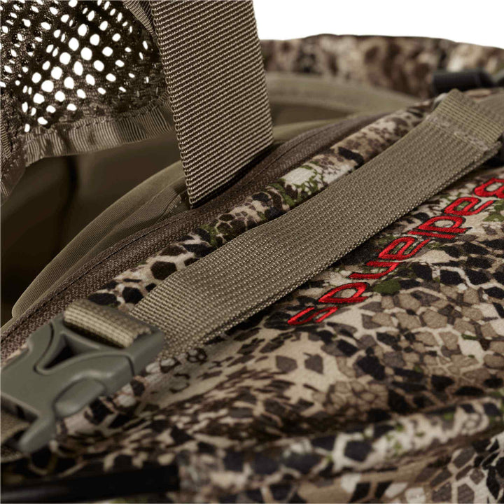 Close-up of a Badlands camo backpack with mesh, strap, buckle, and red Badlands logo featuring the skull emblem.