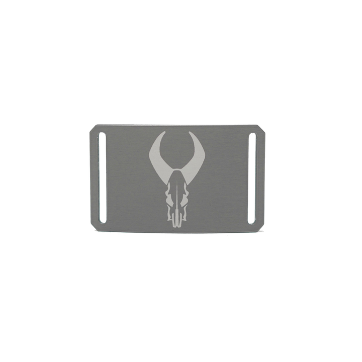 Rectangular metal belt buckle with Badlands skull logo engraved in center; two side slots for strap attachment.